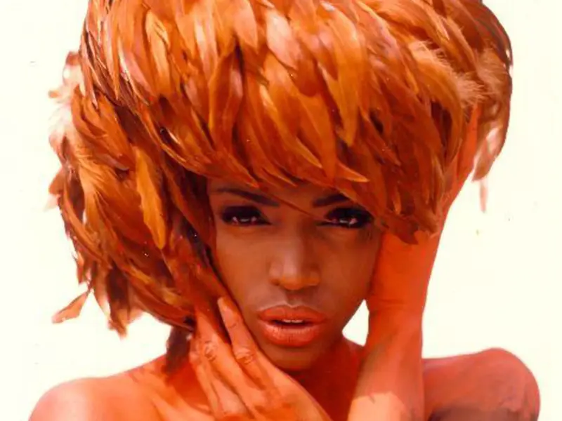 Close-up portrait of model Coco Mitchell with short textured hair and her hands near her face